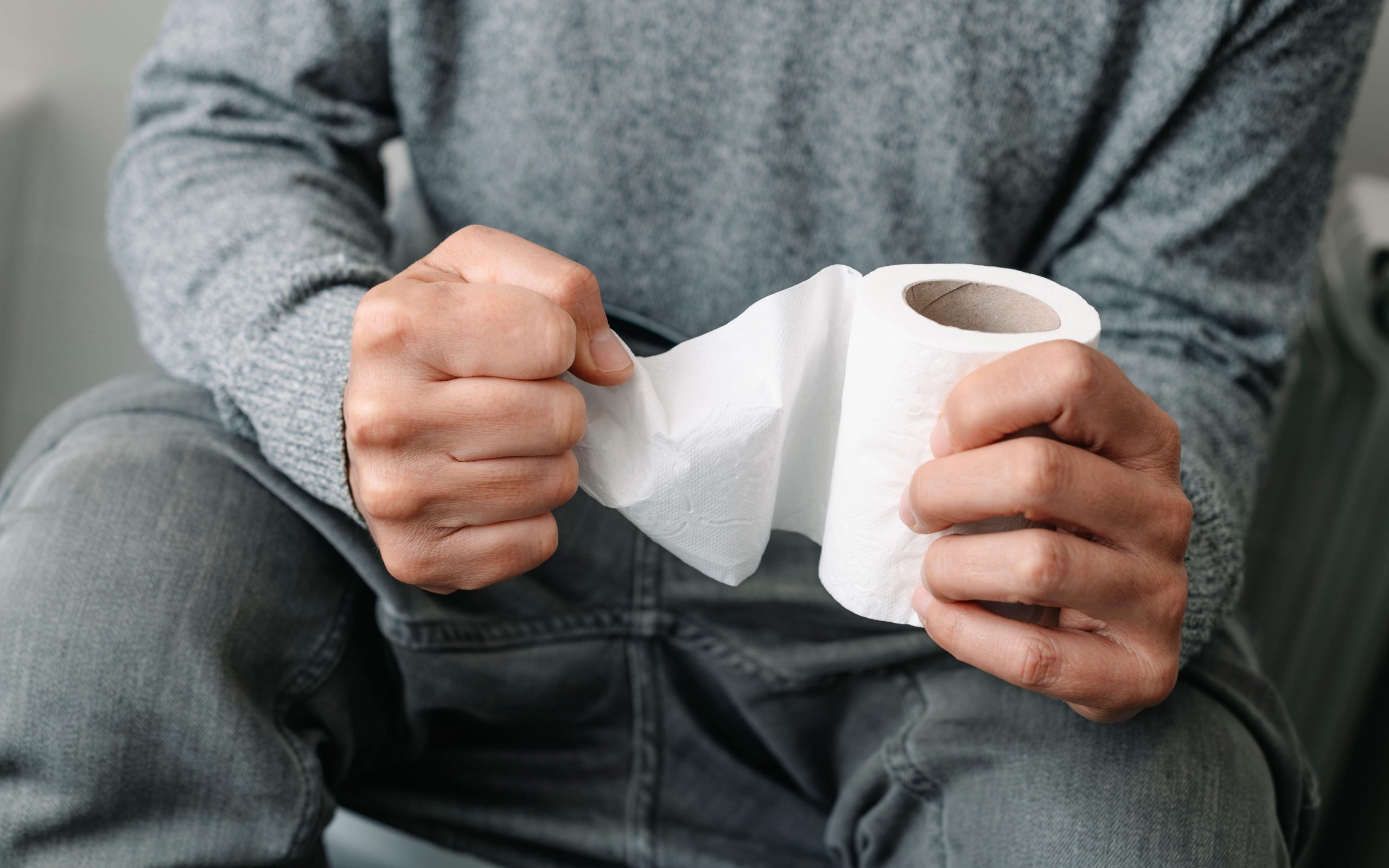 Constipated man holding toilet roll. 