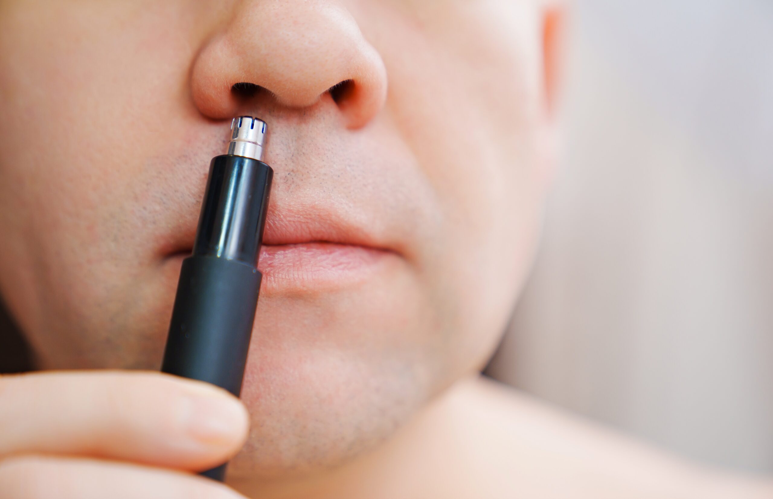 Man using trimmer on nose. 