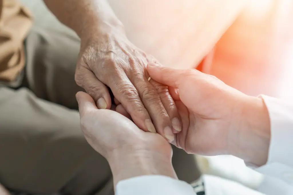 Elderly man holding person's hand.