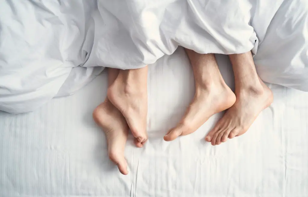 Woman and man under bedsheets. 