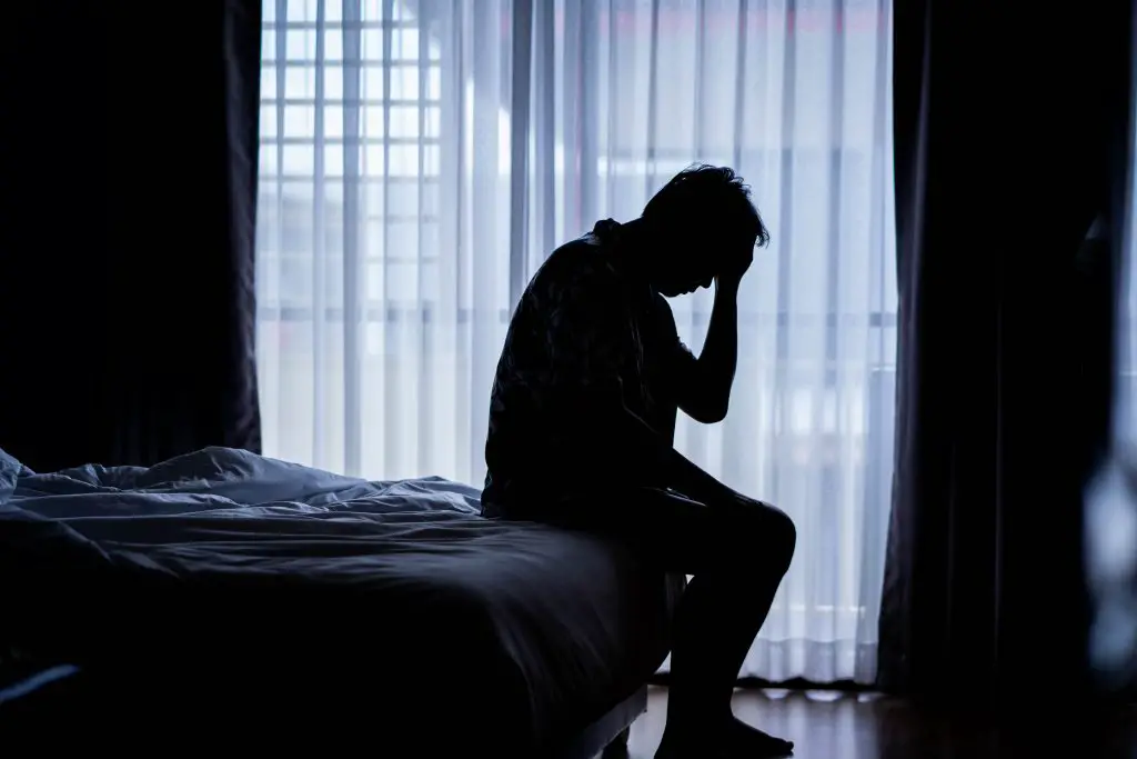 Man stressed sitting on bed. 