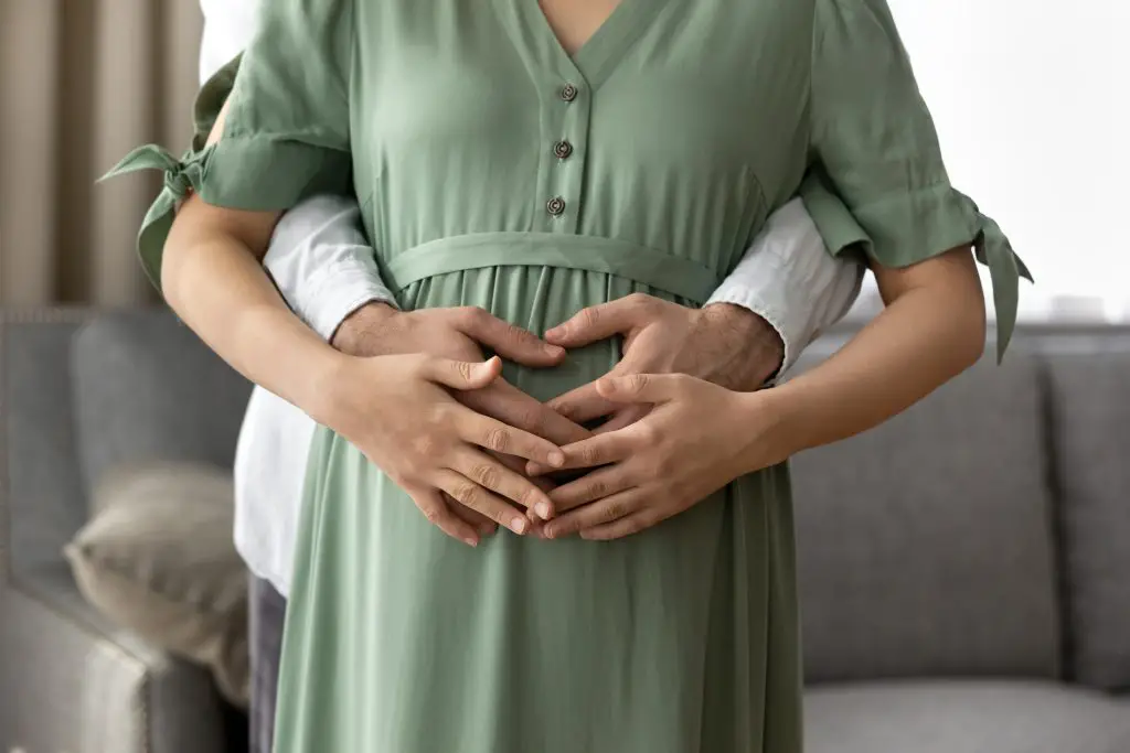 Man holding woman's pregnancy bump.